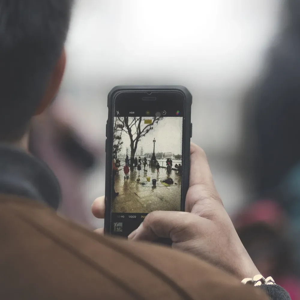 Person seen from behind taking a photo on a smartphone